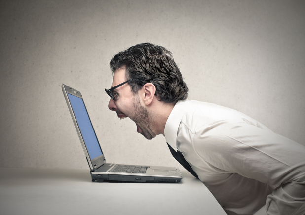 Man wearing glasses yelling at his laptop computer screen- ecommerce business
