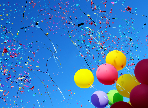 Colorful balloons, streamers and confetti in clear blue sky - USPS price change shipping savings
