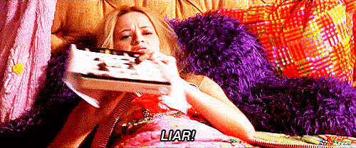 Girl from Legally Blonde movie lying in bed, throwing a box of chocolates at her television and yelling, "Liar!"