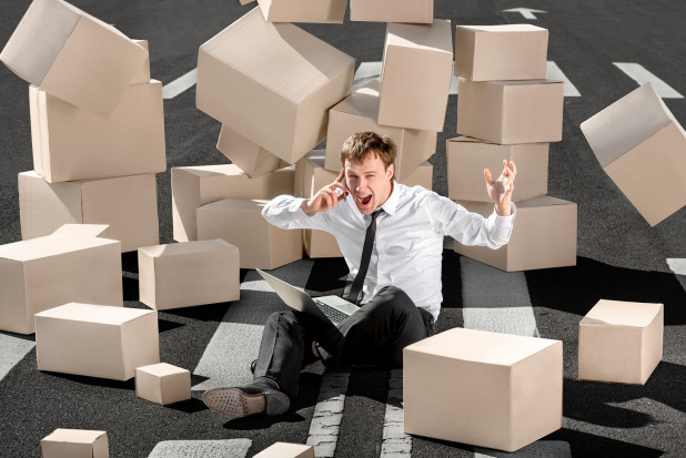 Man sitting on ground surrounded by boxes – need for ecommerce businesses to have inventory management software/system