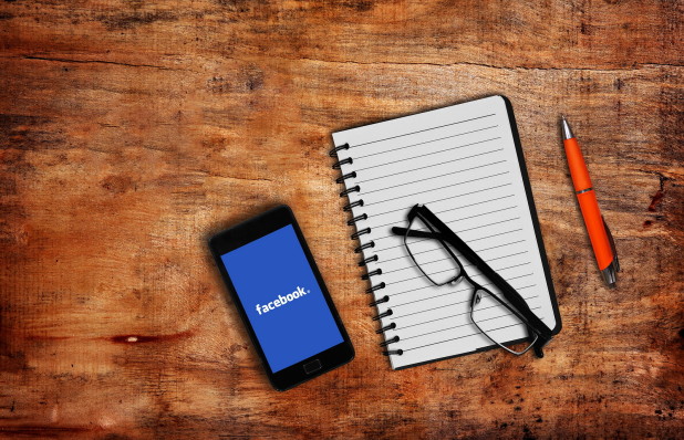 : Notepad, glasses and a mobile phone with Facebook app – Facebook marketing tips and business growth strategies for online businesses.