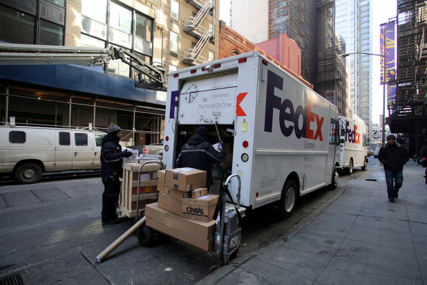 FedEx truck in busy street – FedEx and UPS fuel surcharges and international shipping rates are impacting 2015 holiday shipping season
