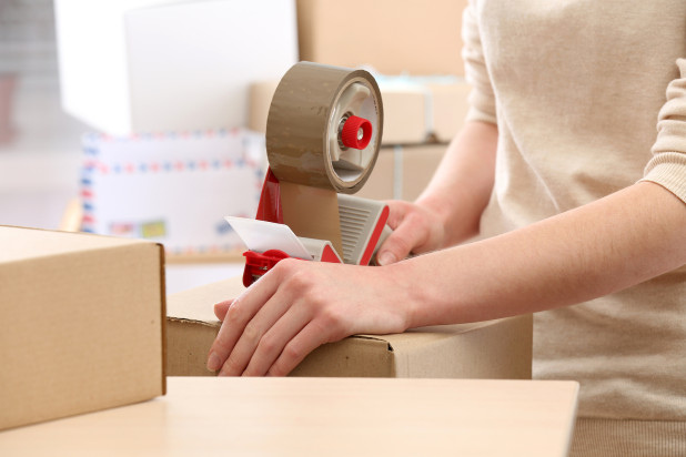 Person packaging a product – how to reduce shipping costs with effective product packaging