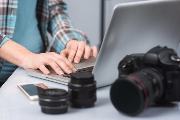 Person using laptop and photography equipment